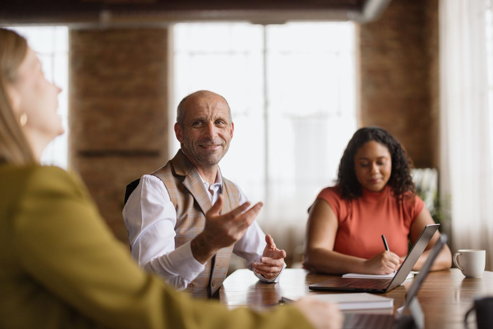 Three colleagues in a lively discussion around a conference table